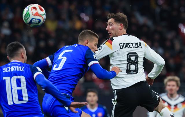 17 November 2025, Saxony, Leipzig: Germany's Leon Goretzka (R) takes on Slovakia's Lubomir Satka and Slovakia's Ivan Schranz battle for the ball during the FIFA World Cup European qualifying match between Germany and Slovakia at Red Bull Arena. Photo: Jan Woitas/dpa
