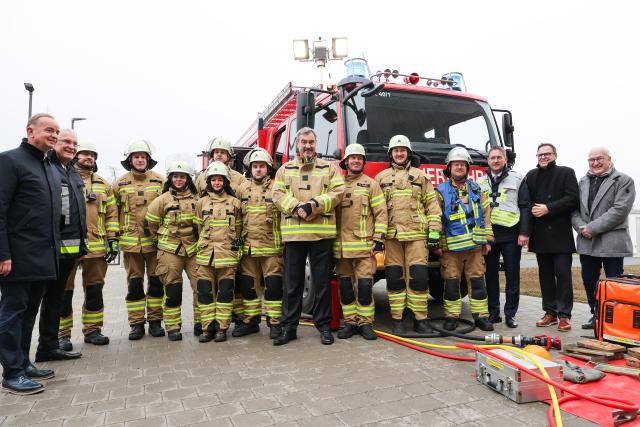 18 November 2025, Bavaria, Ansbach-Brodswinden: Bavaria's Minister President Markus Soeder (C) stands in front of an emergency vehicle at the new integrated control center for the districts of Ansbach and Neustadt/Aisch with members of the fire department in firefighter jackets. Photo: Daniel Löb/dpa