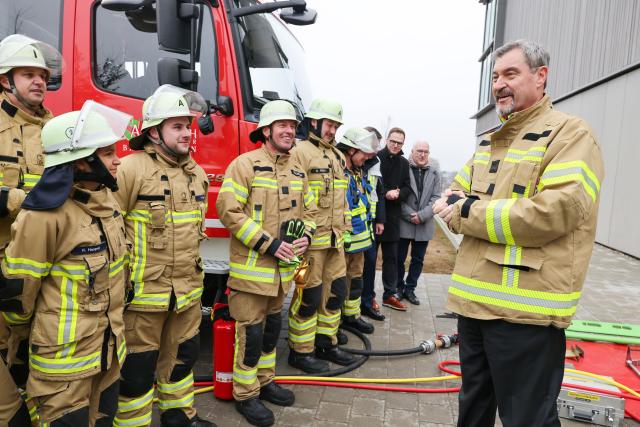 18 November 2025, Bavaria, Ansbach-Brodswinden: Bavaria's Minister President Markus Soeder (R) wearing a firefighter's jacket, talks to members of the fire department at the new integrated control center (ILS) for the districts of Ansbach and Neustadt/Aisch. Photo: Daniel Löb/dpa