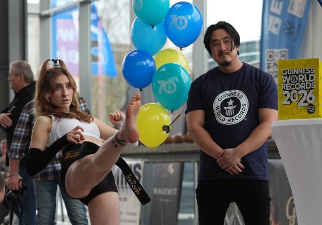 18 November 2025, Hamburg: Palina Glebova (L) throws a dart with her foot to Alexander (Not Pictured) during Guinness World Records Day 2025 at Elbtor Mobile. Glebova and Alexander set a new record in the team record discipline "Most darts thrown with the foot and caught with the hand in the air in one minute". Photo: Marcus Brandt/dpa