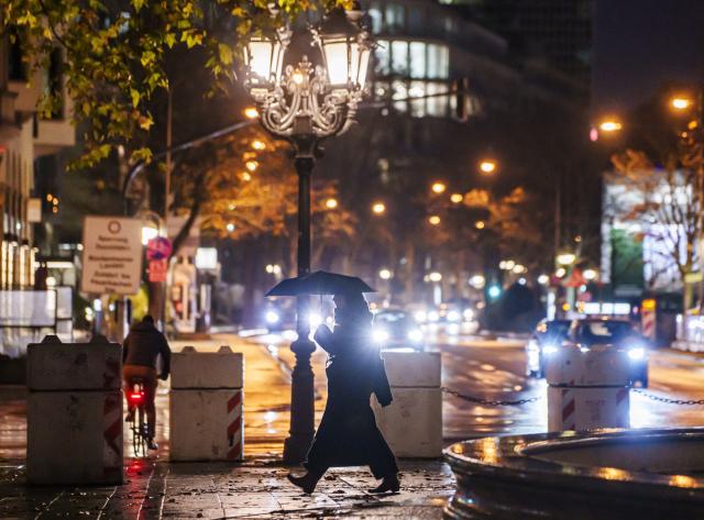 19 November 2025, Hesse, Frankfurt/Main: A woman walks through the city center with an umbrella in the rain. Photo: Andreas Arnold/dpa
