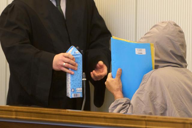 19 November 2025, Rhineland-Palatinate, Koblenz: A lawyer hands water to one of the defendants in the courtroom of the Higher Regional Court. Five defendants are accused of being actively involved in the Syrian civil war between 2012 and 2014 as members of militias loyal to the regime or the Syrian military intelligence service. Photo: Thomas Frey/dpa