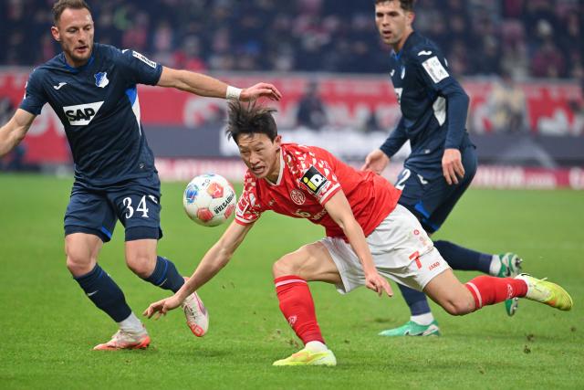 21 November 2025, Rhineland-Palatinate, Mainz: Mainz' Jae-sung Lee and Hoffenheim's Vladimir Coufal (L) and Robin Hranac battle for the ball German Bundesliga FSV Mainz 05 and TSG 1899 Hoffenheim at the Mewa Arena. Photo: Torsten Silz/dpa