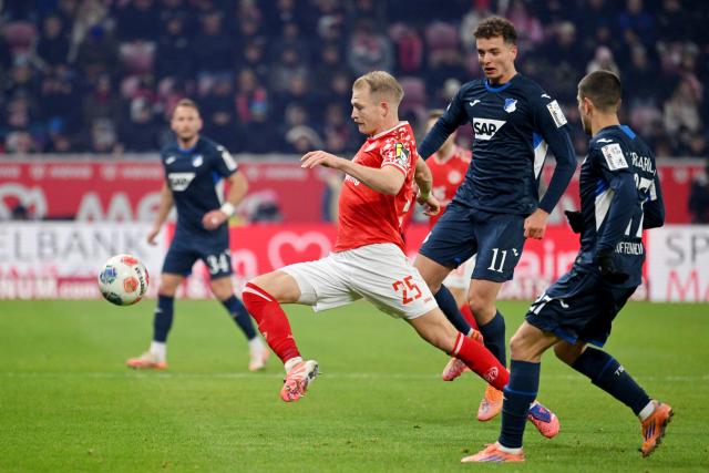 21 November 2025, Rhineland-Palatinate, Mainz: Mainz' Andreas Hanche-Olsen battles for the ball with Hoffenheim's Fisnik Asllani and Andrej Kramari battle for the ball German Bundesliga FSV Mainz 05 and TSG 1899 Hoffenheim at the Mewa Arena. Photo: Torsten Silz/dpa