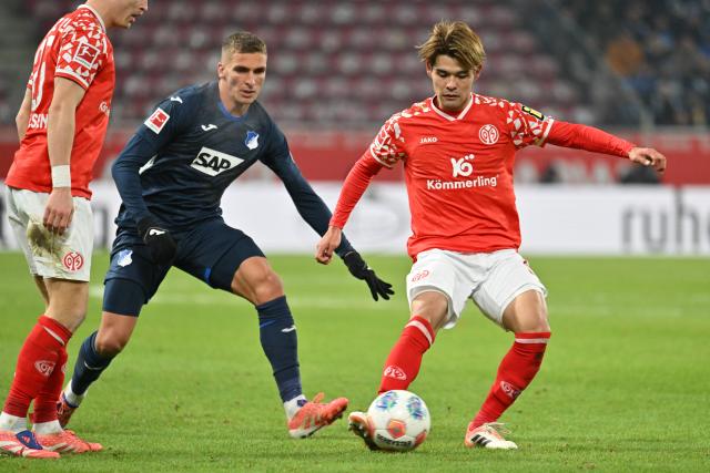 21 November 2025, Rhineland-Palatinate, Mainz: Mainz' Kaishu Sano and Hoffenheim's Grischa Proemel battle for the ball during the German Bundesliga FSV Mainz 05 and TSG 1899 Hoffenheim at the Mewa Arena. Photo: Torsten Silz/dpa