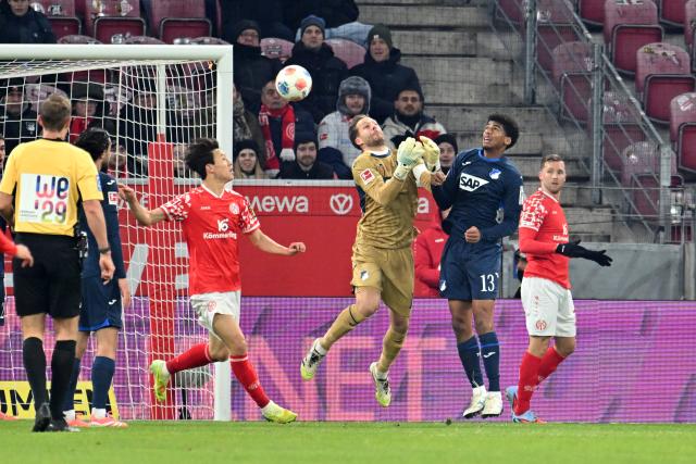 21 November 2025, Rhineland-Palatinate, Mainz: Hoffenheim's Goalkeeper Oliver Baumann (C) goes for the ball in front of his teammates Bernardo (R) and Jae-sung Lee (L) during the German Bundesliga FSV Mainz 05 and TSG 1899 Hoffenheim at the Mewa Arena. Photo: Torsten Silz/dpa