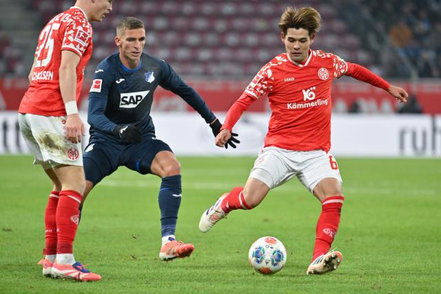 21 November 2025, Rhineland-Palatinate, Mainz: Mainz' Kaishu Sano Hoffenheim's Grischa Proemel battle for the ball during the German Bundesliga FSV Mainz 05 and TSG 1899 Hoffenheim at the Mewa Arena. Photo: Torsten Silz/dpa