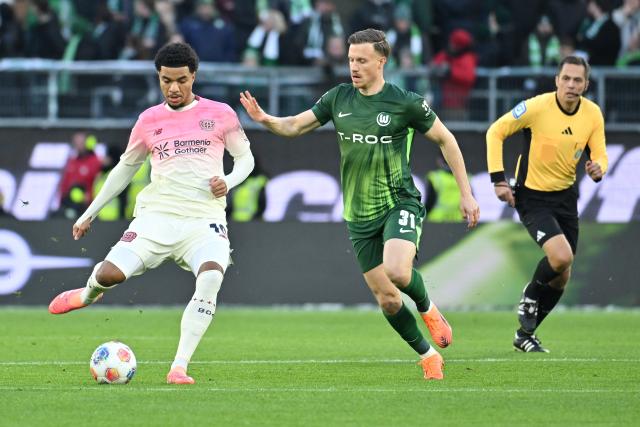 22 November 2025, Wolfsburg: Bayer Leverkusen's Malik Tillman (L) and Wolfsburg's Yannick Gerhardt battle for the ball during the German Bundesliga soccer match between VfL Wolfsburg and Bayer Leverkusen at the Volkswagen Arena. Photo: Swen Pförtner/dpa - IMPORTANT NOTICE: DFL and DFB regulations prohibit any use of photographs as image sequences and/or quasi-video.