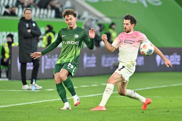 22 November 2025, Wolfsburg: Wolfsburg's Aaron Zehnter (L) and Bayer Leverkusen's Jonas Hofmann battle for the ball during the German Bundesliga soccer match between VfL Wolfsburg and Bayer Leverkusen at the Volkswagen Arena. Photo: Swen Pförtner/dpa - IMPORTANT NOTICE: DFL and DFB regulations prohibit any use of photographs as image sequences and/or quasi-video.
