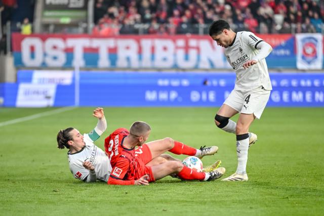22 November 2025, Baden-Württemberg, Heidenheim: Moenchengladbach's Rocco Reitz and Kevin Diks in action against Heidenheim's Adrian Beck during the German Bundesliga soccer match between FC Heidenheim and Borussia Moenchengladbach at the Voith-Arena. Photo: Harry Langer/dpa - IMPORTANT NOTE: In accordance with the regulations of the DFL German Football League and the DFB German Football Association, it is prohibited to utilize or have utilized photographs taken in the stadium and/or of the match in the form of sequential images and/or video-like photo series.