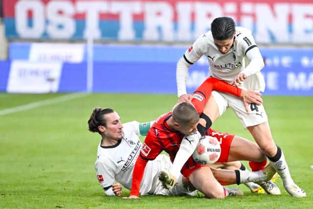 22 November 2025, Baden-Württemberg, Heidenheim: Moenchengladbach's Rocco Reitz and Kevin Diks in action against Heidenheim's Adrian Beck during the German Bundesliga soccer match between FC Heidenheim and Borussia Moenchengladbach at the Voith-Arena. Photo: Harry Langer/dpa - IMPORTANT NOTICE: DFL and DFB regulations prohibit any use of photographs as image sequences and/or quasi-video.