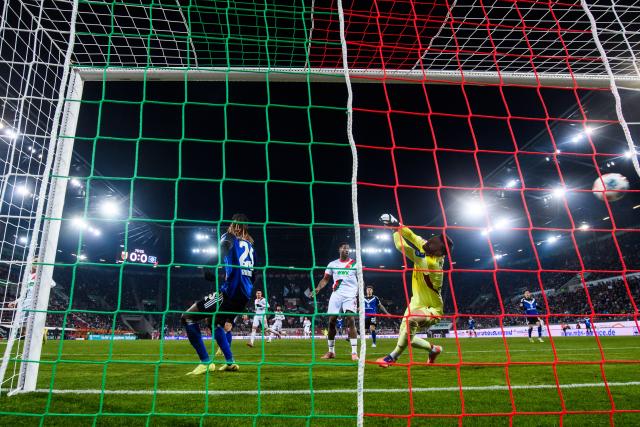 22 November 2025, Bavaria, Augsburg: Augsburg's Anton Kade (L) scores his side's first goal past Hamburger goalkeeper Daniel Heuer Fernandes during the German Bundesliga soccer mat
ch between FC Augsburg and Hamburger SV at the WWK-Arena. Photo: Tom Weller/dpa - IMPORTANT NOTICE: DFL and DFB regulations prohibit any use of photographs as image sequences and/or quasi-video.