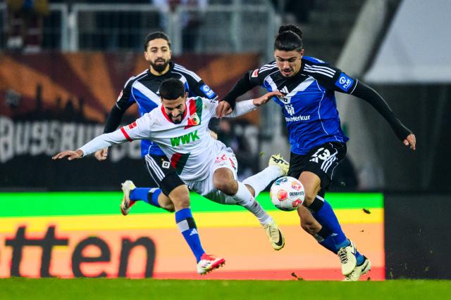 22 November 2025, Bavaria, Augsburg: Augsburg's Elias Saad in action against Hamburger's Guilherme Ramos during the German Bundesliga soccer match between FC Augsburg and Hamburger SV at the WWK-Arena. Photo: Tom Weller/dpa - IMPORTANT NOTICE: DFL and DFB regulations prohibit any use of photographs as image sequences and/or quasi-video.