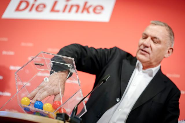 24 November 2025, Berlin: Jan van Aken, party chairman of the Left Party, spins a lottery drum with names of members of the Bundestag during the press conference of the Left Party in the Karl Liebknecht House on the subject of compulsory military service for a symbolic drawing of conscripts. Photo: Kay Nietfeld/dpa