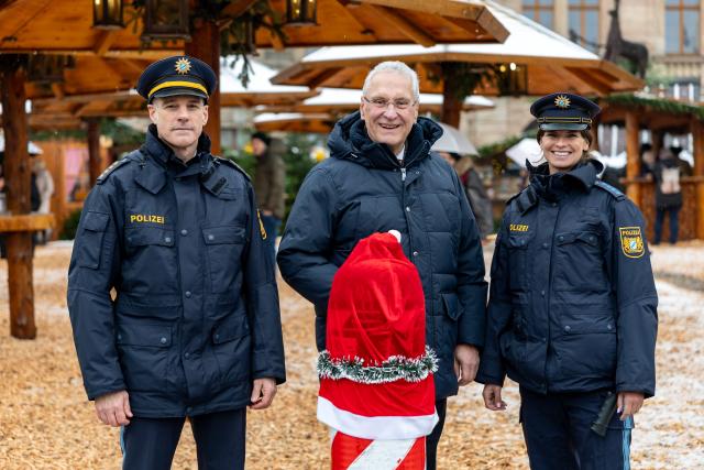 24 November 2025, Bavaria, Erlangen: Bavarian Minister of the Interior Joachim Herrmann (C) stands with Head of the Erlangen City Police Department Klaus Wild and police officer Kerstin Decker in front of a security bollard at the Erlangen Forest Christmas Market. Photo: Daniel Karmann/dpa