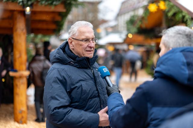 24 November 2025, Bavaria, Erlangen: Bavarian Interior Minister Joachim Herrmann (L) gives an interview on security at Bavarian Christmas markets at the Erlangen Waldweihnacht. Photo: Daniel Karmann/dpa