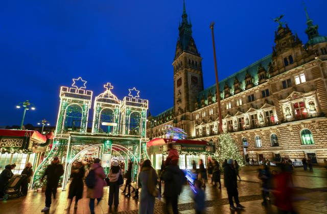 24 November 2025, Hamburg: Visitors head to the colorfully illuminated Hamburg's Christmas market in front of the town hall. Christmas market opened on the Rathausmarkt on Monday. Photo: Christian Charisius/dpa