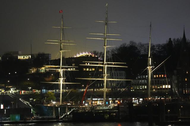 25 November 2025, Hamburg: The brightly lit Ferris wheel at the Hamburg Winter Dome can be seen between the masts of the museum ship "Rickmer Rickmers" from the harbor. Photo: Marcus Brandt/dpa
