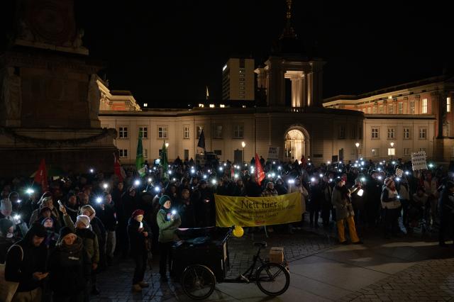 25 November 2025, Brandenburg, Potsdam: People hold up their lit cell phones during a demonstration in Potsdam, marking the second anniversary of the meeting of right-wing circles. Photo: Markus Lenhardt/dpa
