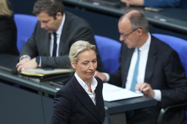 26 November 2025, Berlin: Alice Weidel, parliamentary group and federal leader of the AfD, walks past Federal Finance Minister Lars Klingbeil (SPD) and Federal Chancellor Friedrich Merz (CDU) to the lectern during the general debate in the Bundestag on the budget. The debates on the budget of the Chancellery are traditionally used as a general debate on the policies of the Federal Government. Photo: Michael Kappeler/dpa