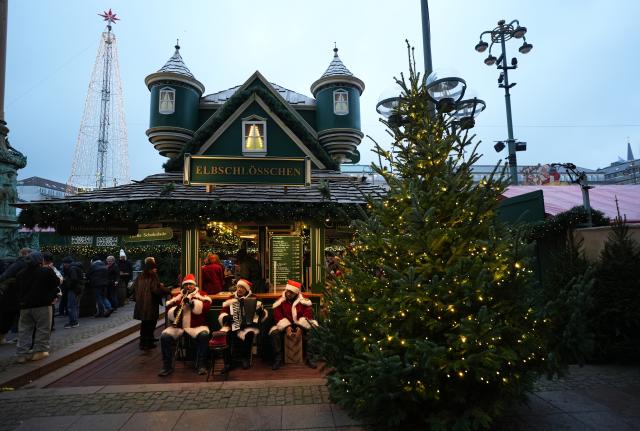 26 November 2025, Hamburg: Three musicians in Santa Claus costumes play music at the Christmas market on the Rathausmarkt. Photo: Marcus Brandt/dpa
