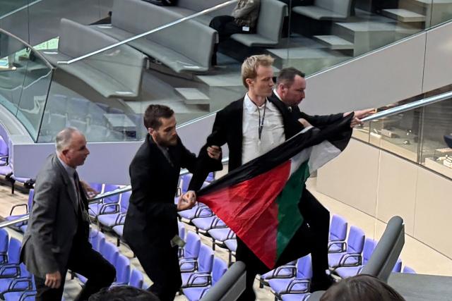 26 November 2025, Berlin: A man holding a Palestinian flag is led out by security personnel during the general debate on the budget in the Bundestag. Photo: Elisa Schu/dpa