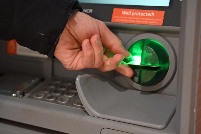 FILED - 12 March 2025, Saxony, Leipzig: A man pulls his bank card out of the dispenser of an ATM. Photo: Elisa Schu/dpa