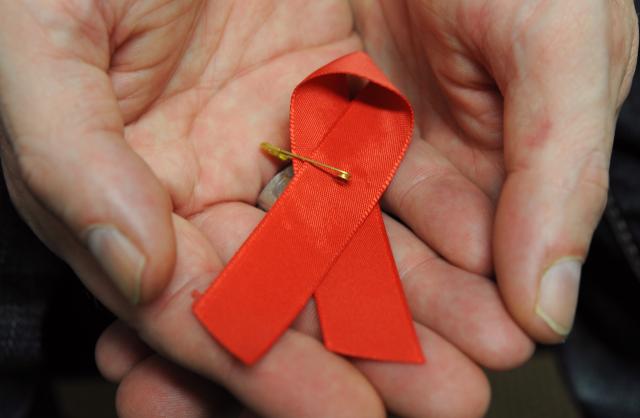 FILED - 22 November 2012, Hesse, Frankfurt/Main: A man infected with the HI virus holds a red ribbon as a symbol of solidarity with HIV-positive and AIDS patients. Photo: Arne Dedert/dpa