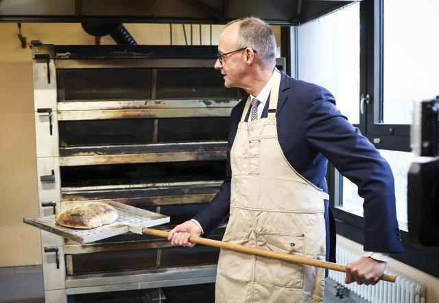 FILED - 25 November 2025, Hamburg: German Chancellor Friedrich Merz takes bread out of an oven at the bakery of bread manufacturer Soeren Korte during his visit to the Meistermeile craftsmen's yard, as part of his inaugural visit to Hamburg. Photo: Christian Charisius/dpa