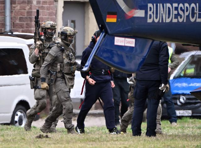 28 November 2025, Baden-Württemberg, Karlsruhe: A person is led to a helicopter. A suspected mastermind of the attacks on the Nord Stream gas pipelines had previously had a detention hearing at the investigating judge of the Federal Court of Justice (BGH) in Karlsruhe. Photo: Uli Deck/dpa