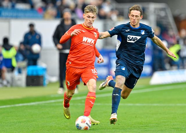29 November 2025, Baden-Wuerttemberg, Sinsheim: Hoffenheim's Wouter Burger (R) and Augsburg's Anton Kade battle for the ball during the German Bundesliga soccer match between TSG 1899 Hoffenheim and FC Augsburg at PreZero Arena. Photo: Uwe Anspach/dpa - WICHTIGER HINWEIS: Gemäß den Vorgaben der DFL Deutsche Fußball Liga bzw. des DFB Deutscher Fußball-Bund ist es untersagt, in dem Stadion und/oder vom Spiel angefertigte Fotoaufnahmen in Form von Sequenzbildern und/oder videoähnlichen Fotostrecken zu verwerten bzw. verwerten zu lassen.