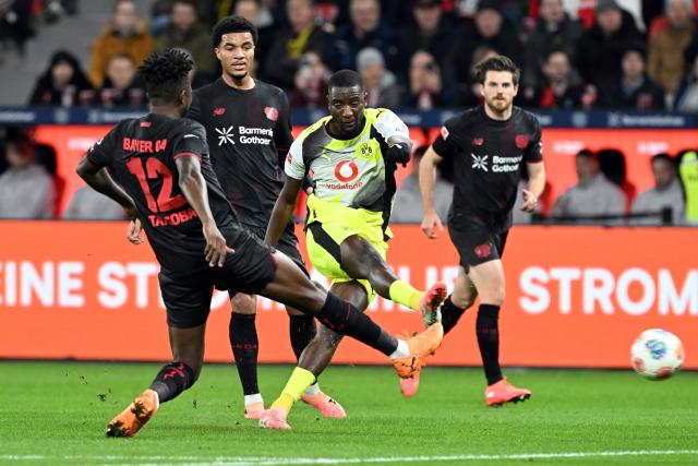 29 November 2025, North Rhine-Westphalia, Leverkusen: Bayer Leverkusen's Edmond Tapsoba (L) and Borussia Dortmund's Serhou Guirassy battle for the ball during the German Bundesliga soccer match between Bayer Leverkusen and Borussia Dortmund at BayArena. Photo: Federico Gambarini/dpa - WICHTIGER HINWEIS: Gemäß den Vorgaben der DFL Deutsche Fußball Liga bzw. des DFB Deutscher Fußball-Bund ist es untersagt, in dem Stadion und/oder vom Spiel angefertigte Fotoaufnahmen in Form von Sequenzbildern und/oder videoähnlichen Fotostrecken zu verwerten bzw. verwerten zu lassen.