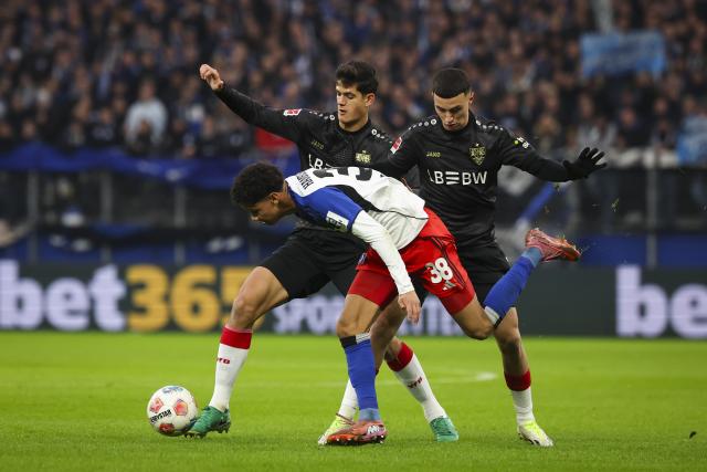 30 November 2025, Hamburg: Hamburger's Alexander Rossing-Lelesiit and Stuttgart's Chema Andres (L) and VfB Stuttgart's Bilal El Khannouss during the German Bundesliga soccer match between Hamburger SV and VfB Stuttgart at the Volksparkstadion. Photo: Christian Charisius/dpa - IMPORTANT NOTICE: DFL and DFB regulations prohibit any use of photographs as image sequences and/or quasi-video.