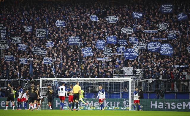 30 November 2025, Hamburg: Soccer fans hold signs to protest against the planned political measures for security in stadiums, during the German Bundesliga soccer match between Hamburger SV and VfB Stuttgart at the Volksparkstadion. Photo: Christian Charisius/dpa - IMPORTANT NOTICE: DFL and DFB regulations prohibit any use of photographs as image sequences and/or quasi-video.