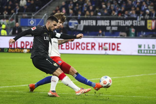 30 November 2025, Hamburg: Stuttgart's Deniz Undav (L) and Hamburger's Mario Vuskovic battle for the ball during the German Bundesliga soccer match between Hamburger SV and VfB Stuttgart at the Volksparkstadion. Photo: Christian Charisius/dpa - IMPORTANT NOTICE: DFL and DFB regulations prohibit any use of photographs as image sequences and/or quasi-video.