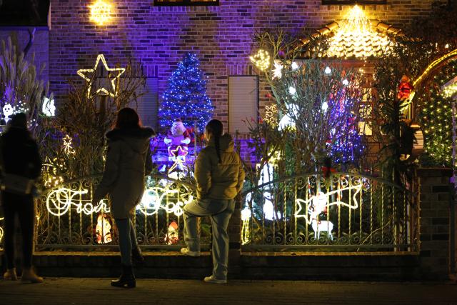 30 November 2025, Saxony-Anhalt, Gatersleben: People look at light installations in the front garden of the Lange family's Christmas house. The house is traditionally decorated with thousands of colorful lights during the Advent season. Photo: Matthias Bein/dpa