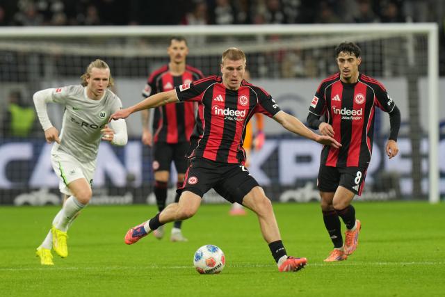 30 November 2025, Hesse, Frankfurt/M.: Wolfsburg's Patrick Wimmer (L) and Eintracht Frankfurt's Rasmus Kristensen battle for the ball during the German Bundesliga soccer match between Eintracht Frankfurt and VfL Wolfsburg at the Deutsche Bank Park. Photo: Thomas Frey/dpa - IMPORTANT NOTICE: DFL and DFB regulations prohibit any use of photographs as image sequences and/or quasi-video.