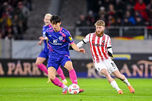 30 November 2025, Baden-Württemberg, Freiburg im Breisgau: Mainz' Jae-sung Lee (L) in and Freiburg's Jan-Niklas Beste battle for the ball during the German Bundesliga soccer match between SC Freiburg and FSV Mainz 05 at Europa-Park Stadium. Photo: Harry Langer/dpa - IMPORTANT NOTICE: DFL and DFB regulations prohibit any use of photographs as image sequences and/or quasi-video.