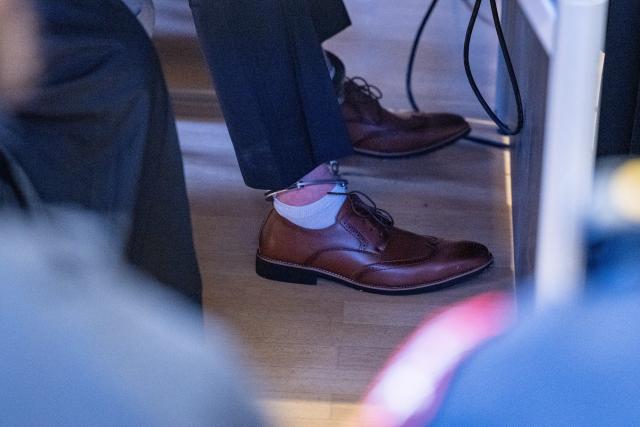 01 December 2025, Bavaria, Regensburg: A defendant sits in the district court courtroom wearing an ankle bracelet. According to the indictment, on August 17, 2024, four men overpowered a district hospital employee to force open a gate and then fled the facility. Photo: Armin Weigel/dpa