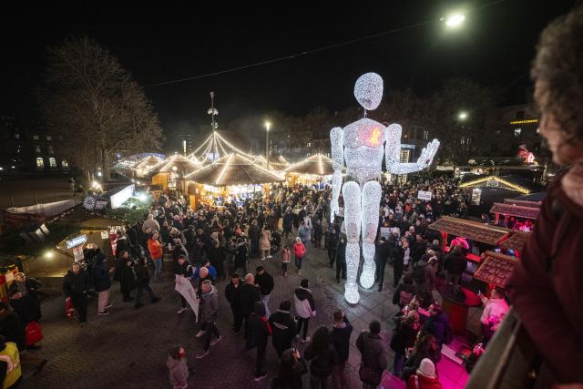 01 December 2025, Baden-Württemberg, Stuttgart: The eight meter high illuminated puppet "Vektor" from the large puppet theater "Dundu" is led by puppeteers around the Christmas market in Stuttgart. The performance of the large puppet accompanied a campaign by AIDS-Hilfe Stuttgart to mark World AIDS Day. Photo: Marijan Murat/dpa