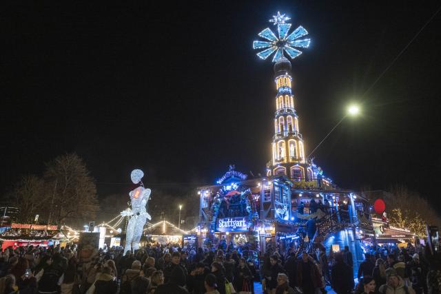 01 December 2025, Baden-Württemberg, Stuttgart: The eight meter high illuminated puppet "Vektor" from the large puppet theater "Dundu" is led by puppeteers around the Christmas market in Stuttgart. The performance of the large puppet accompanied a campaign by AIDS-Hilfe Stuttgart to mark World AIDS Day. Photo: Marijan Murat/dpa