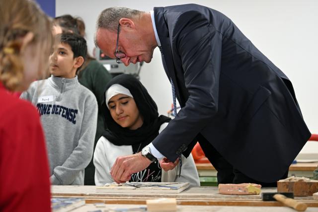 02 December 2025, Thueringen, Jena: German Chancellor Friedrich Merz makes a mosaic with children from the workshop school on the occasion of his inaugural visit to Thuringia. Photo: Jennifer Brückner/dpa