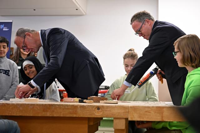 02 December 2025, Thueringen, Jena: German Chancellor Friedrich Merz (L) and Mario Voigt (2-R), Minister President of Thuringia, make a mosaic with children from the workshop school on the occasion of their inaugural visit to Thuringia. Photo: Jennifer Brückner/dpa