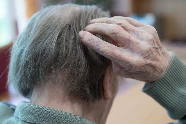 FILED - 10 May 2019, Saxony, Bernsdorf: A man scratches his head in a nursing home. Photo: Sebastian Kahnert/ZB/dpa