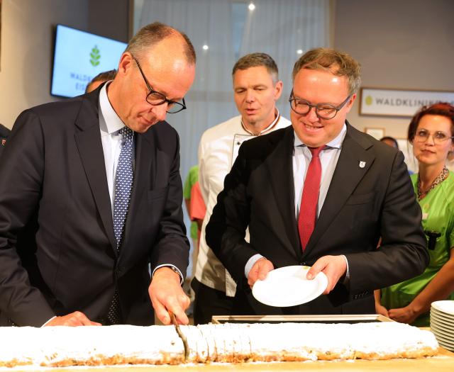 02 December 2025, Thueringen, Eisenberg: German Chancellor Friedrich Merz (L) and Mario Voigt (R), Minister President of Thuringia, cutting a stollen during a visit to the Waldkliniken Eisenberg on the occasion of his inaugural visit to Thuringia. Photo: Bodo Schackow/dpa