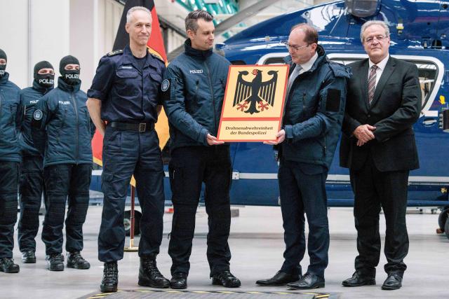02 December 2025, Brandenburg, Ahrensfelde: Alexander Dobrindt (2-R), German Minister of the Interior, hands over the sign with the inscription "Drone Defense Unit of the Federal Police" at the presentation of new defense techniques for drone defense at the Federal Police Air Wing in Blumberg. Photo: Carsten Koall/dpa