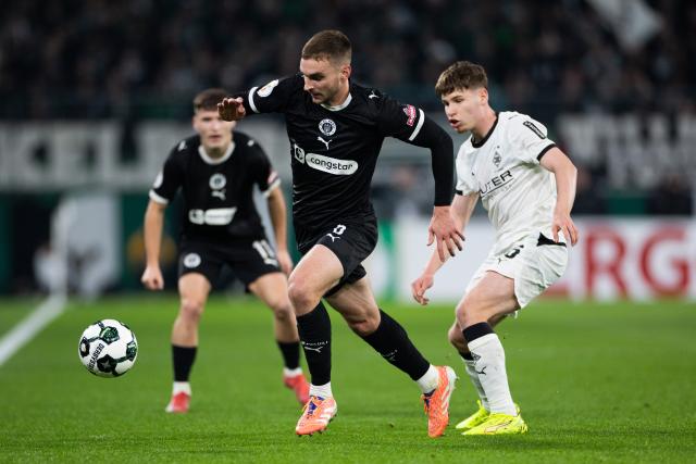02 December 2025, North Rhine-Westphalia, Moenchengladbach: Moenchengladbach's Yannik Engelhardt (R) and Pauli's James Sands battle for the ball during the German DFB Cup round of 16 soccer match between Borussia Moenchengladbach and FC St. Pauli at Borussia-Park. Photo: Rolf Vennenbernd/dpa - IMPORTANT NOTICE: DFL and DFB regulations prohibit any use of photographs as image sequences and/or quasi-video.