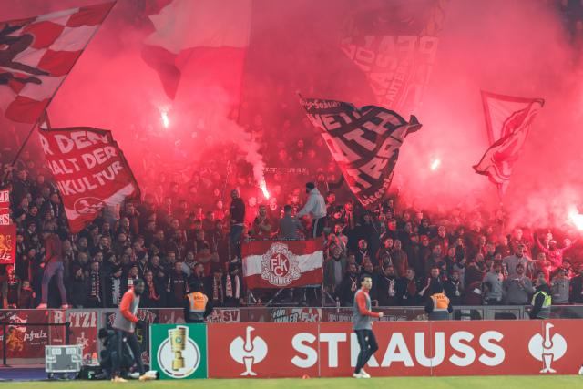 02 December 2025, Berlin: FC Kaiserslautern fans light a Bengal fire during the German DFB Cup round of 16 soccer match between Hertha BSC and 1. FC Kaiserslautern at Olympiastadion. Photo: Andreas Gora/dpa - WICHTIGER HINWEIS: Gemäß den Vorgaben der DFL Deutsche Fußball Liga bzw. des DFB Deutscher Fußball-Bund ist es untersagt, in dem Stadion und/oder vom Spiel angefertigte Fotoaufnahmen in Form von Sequenzbildern und/oder videoähnlichen Fotostrecken zu verwerten bzw. verwerten zu lassen.