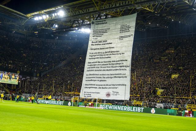 02 December 2025, North Rhine-Westphalia, Dortmund: Dortmund fans protest with a large poster prior to the start of the German DFB Cup soccer match between Borussia Dortmund and Bayer Leverkusen at the Signal Iduna Park. Photo: David Inderlied/dpa - WICHTIGER HINWEIS: Gemäß den Vorgaben der DFL Deutsche Fußball Liga bzw. des DFB Deutscher Fußball-Bund ist es untersagt, in dem Stadion und/oder vom Spiel angefertigte Fotoaufnahmen in Form von Sequenzbildern und/oder videoähnlichen Fotostrecken zu verwerten bzw. verwerten zu lassen.