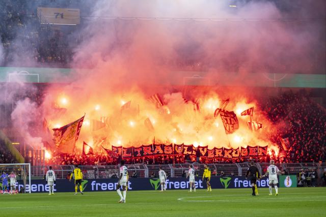 02 December 2025, North Rhine-Westphalia, Dortmund: Leverkusen fans set off pyrotechnics during the German DFB Cup soccer match between Borussia Dortmund and Bayer Leverkusen at the Signal Iduna Park. Photo: David Inderlied/dpa - WICHTIGER HINWEIS: Gemäß den Vorgaben der DFL Deutsche Fußball Liga bzw. des DFB Deutscher Fußball-Bund ist es untersagt, in dem Stadion und/oder vom Spiel angefertigte Fotoaufnahmen in Form von Sequenzbildern und/oder videoähnlichen Fotostrecken zu verwerten bzw. verwerten zu lassen.
